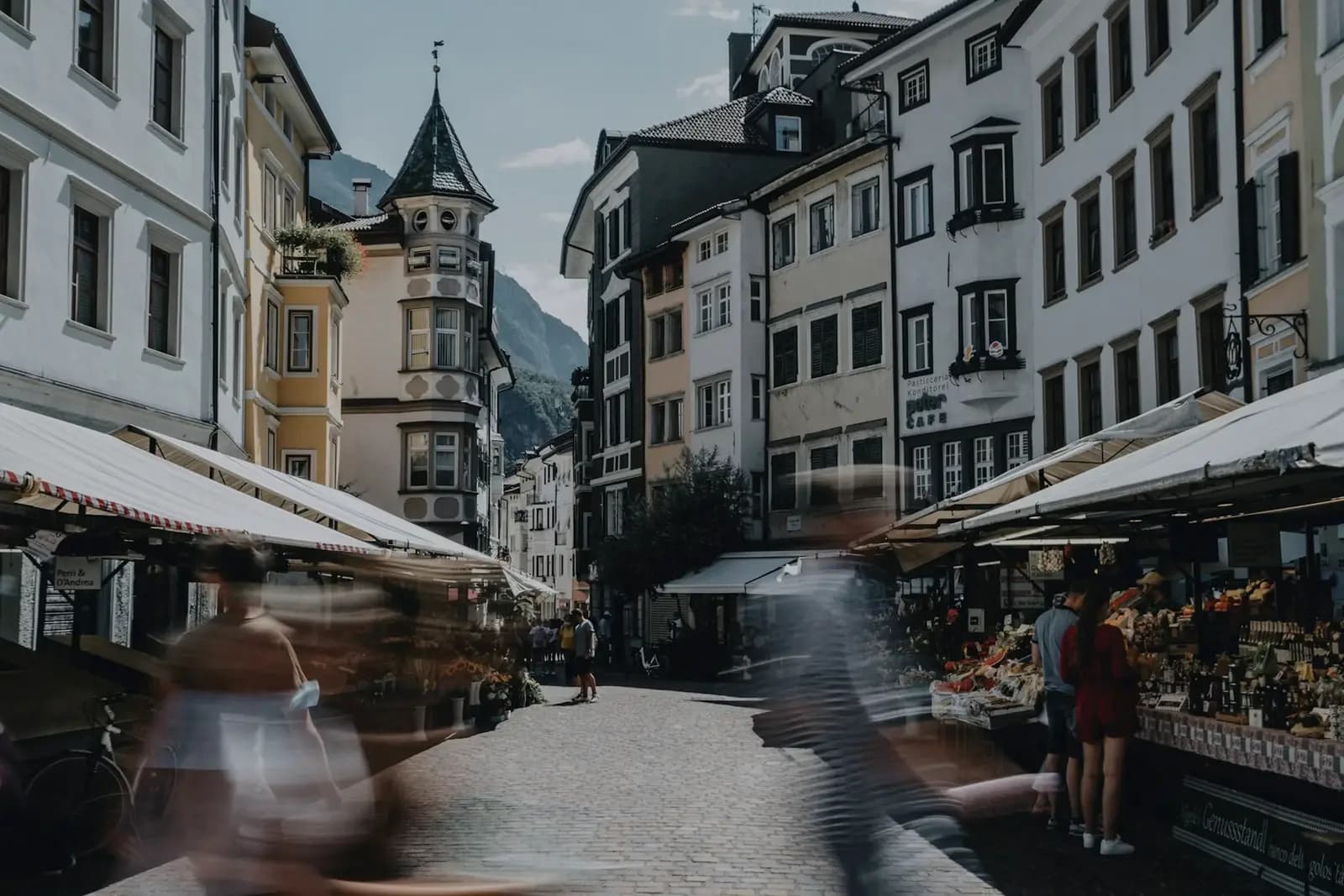 Gasse in der Bozener Altstadt mit Marktständen und Bergen im Hintergrund