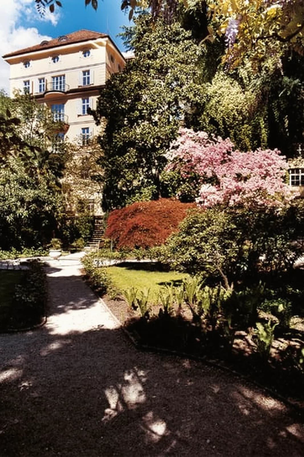 Parkhotel Laurin – Park mit blühenden Bäumen vor dem Haus