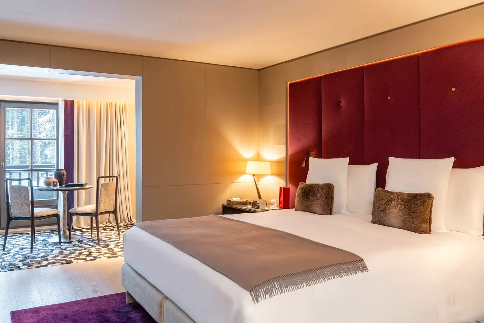 Cheval Blanc Courchevel – Junior Suite mit rotem Kopfteil und Sitzecke