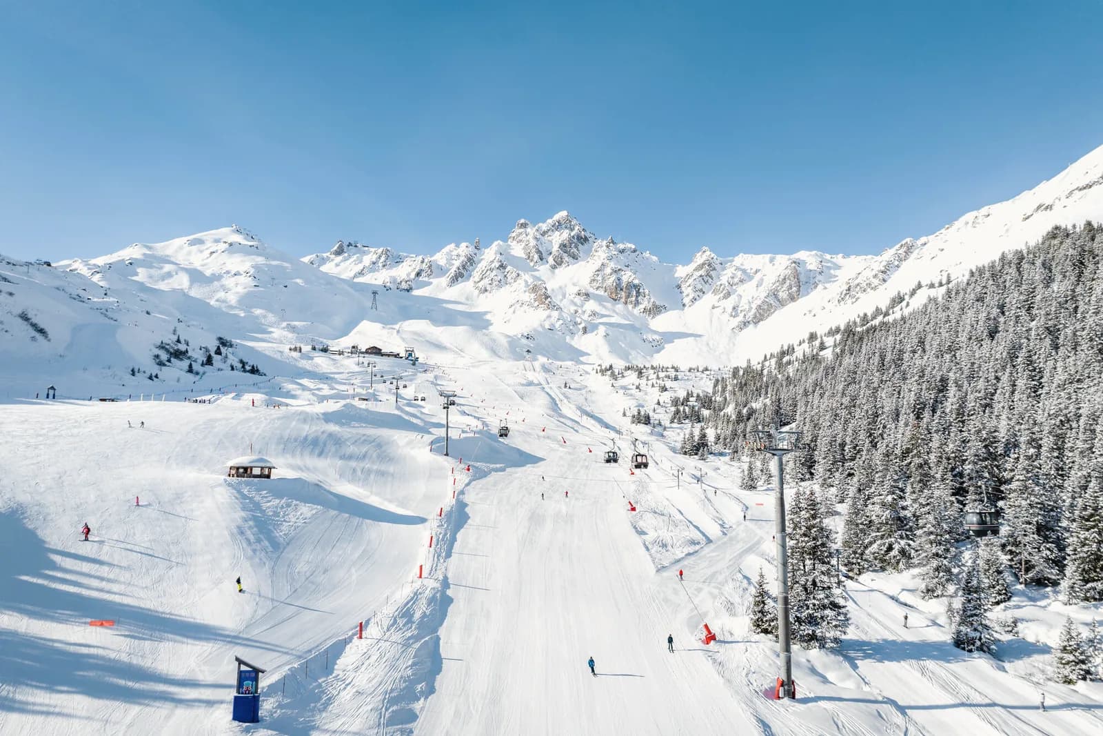 Breite Piste in Courchevel vor den Gipfeln der Trois Vallées