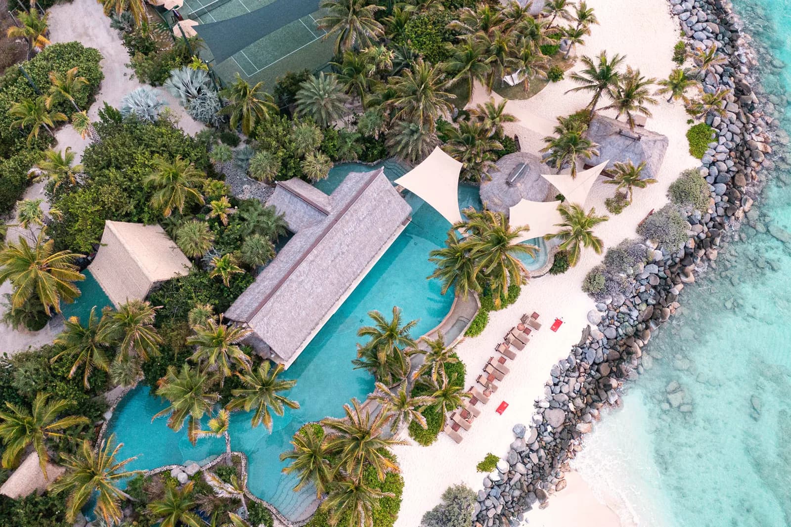Die Poollandschaft der Insel zwischen Palmen aus der Luft