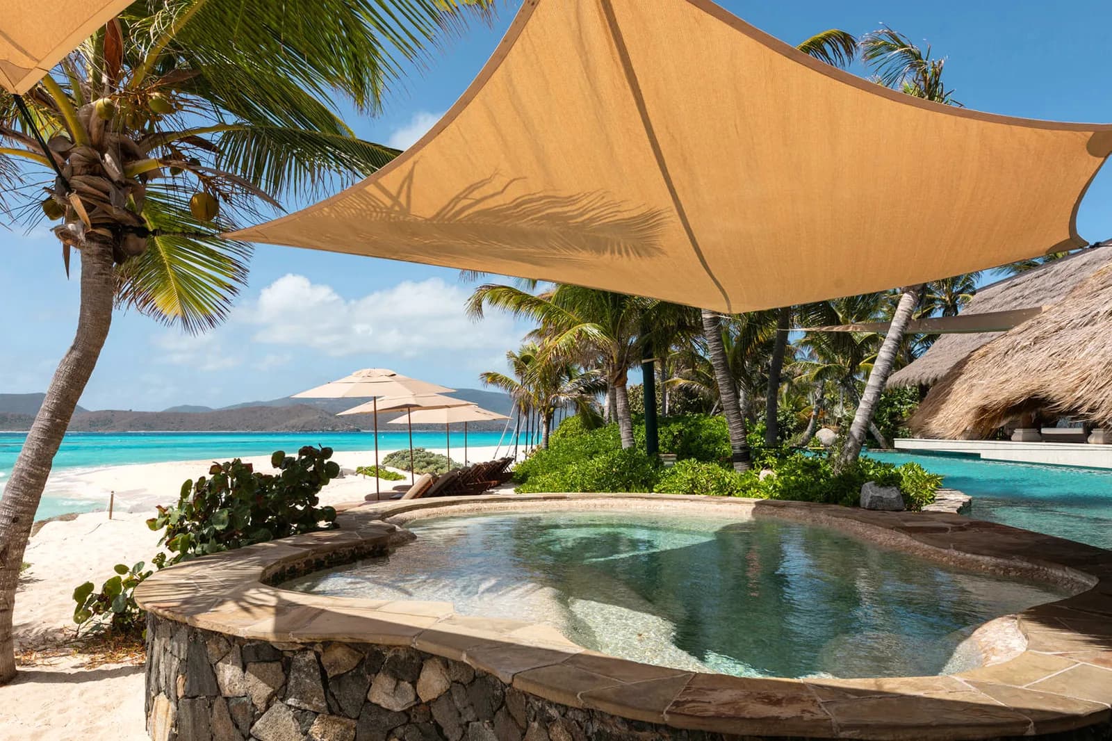 Pool und Sonnensegel über dem weißen Strand von Necker Island