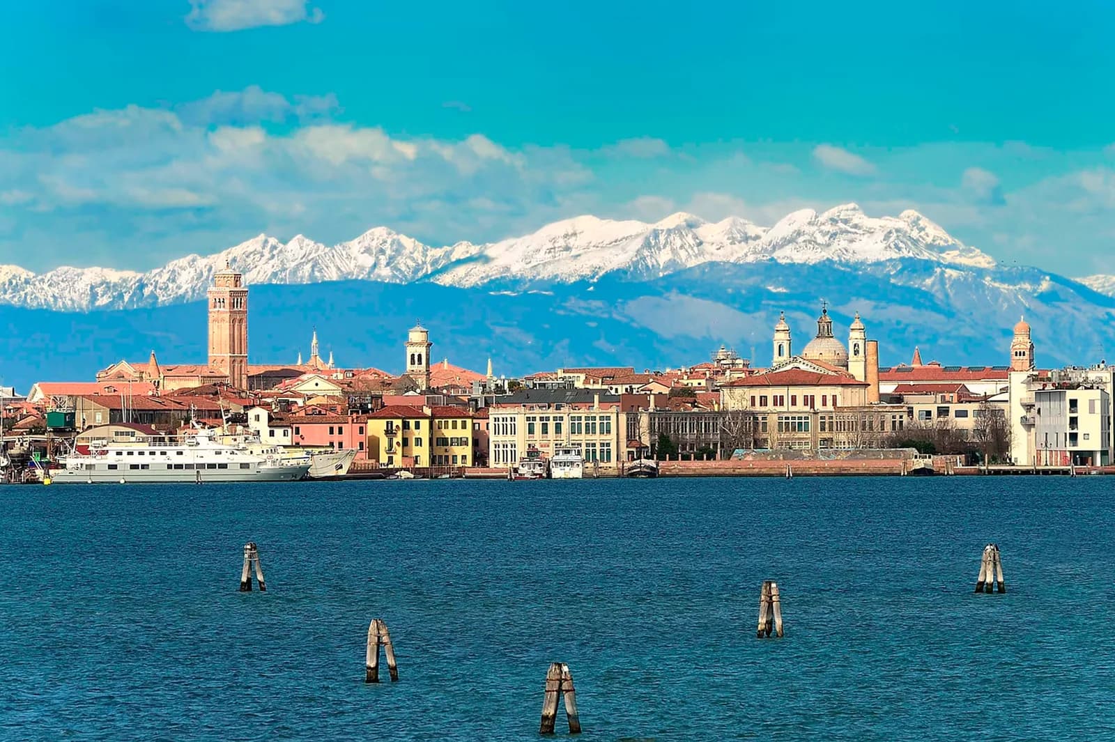 Die Silhouette von Venedig über der Lagune, dahinter die verschneiten Alpen