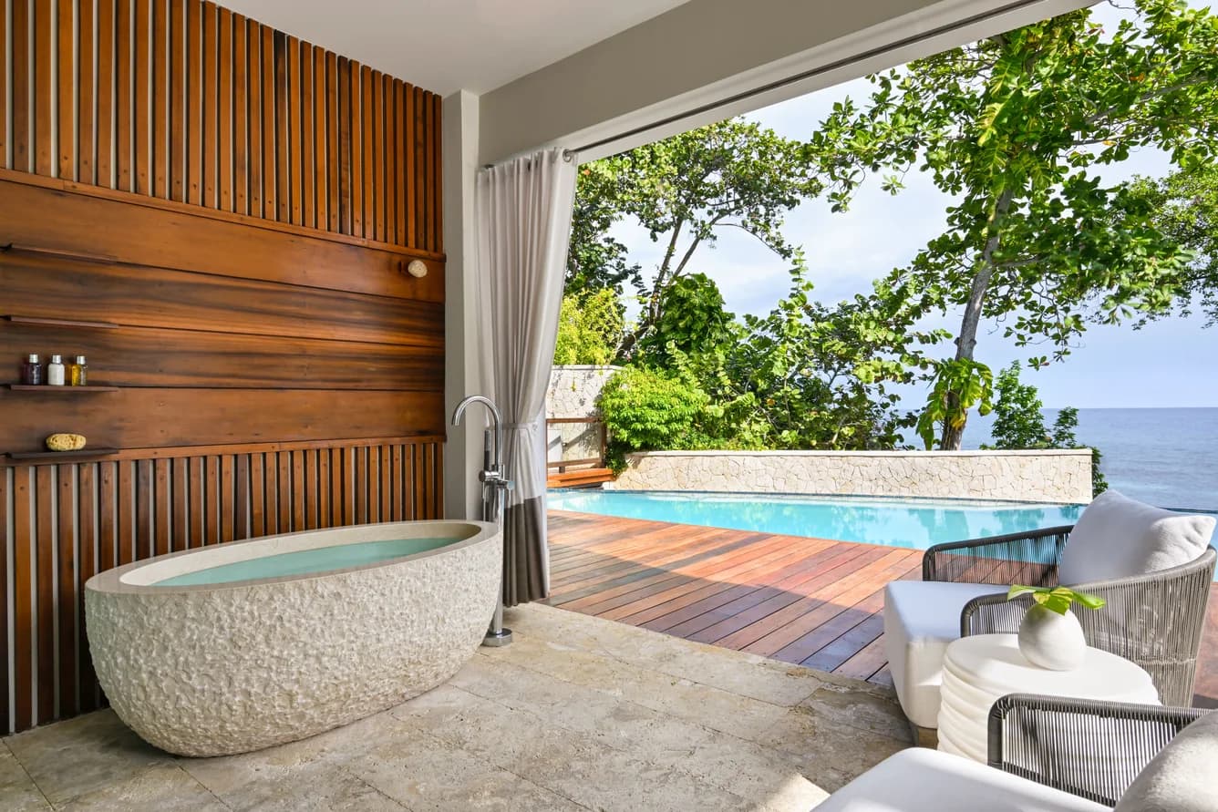 Suite mit freistehender Wanne und Blick zum Pool
