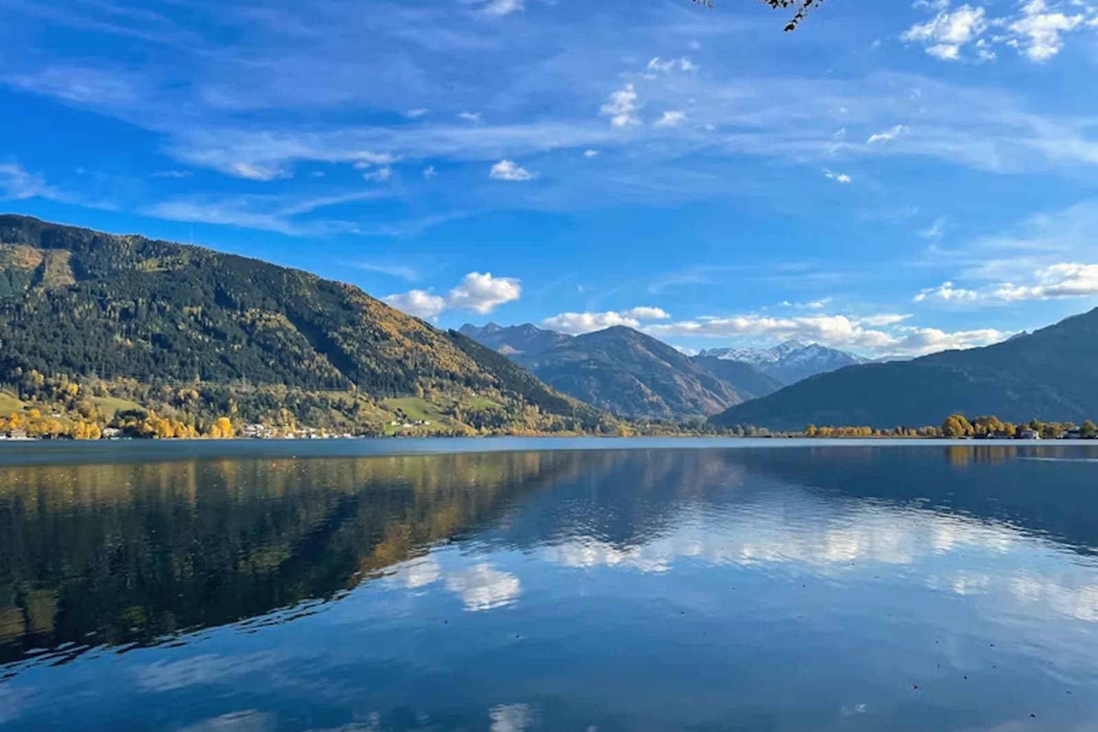 Der Zeller See im Herbst, die Berge spiegeln sich im ruhigen Wasser